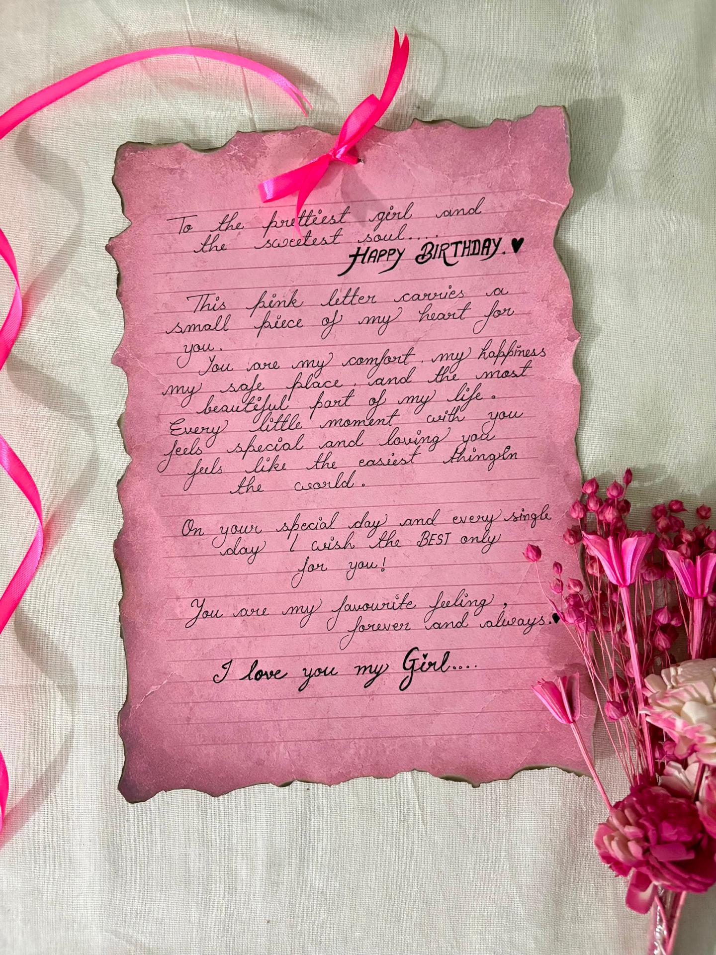 Handwritten birthday letter on pink deckle-edge paper with dried flowers