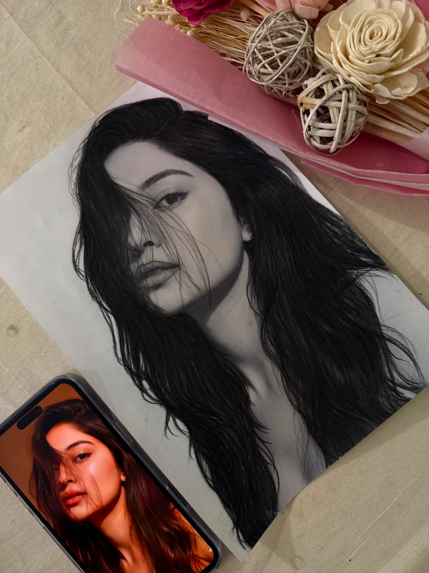 Realistic pencil portrait beside its reference photo and floral arrangement